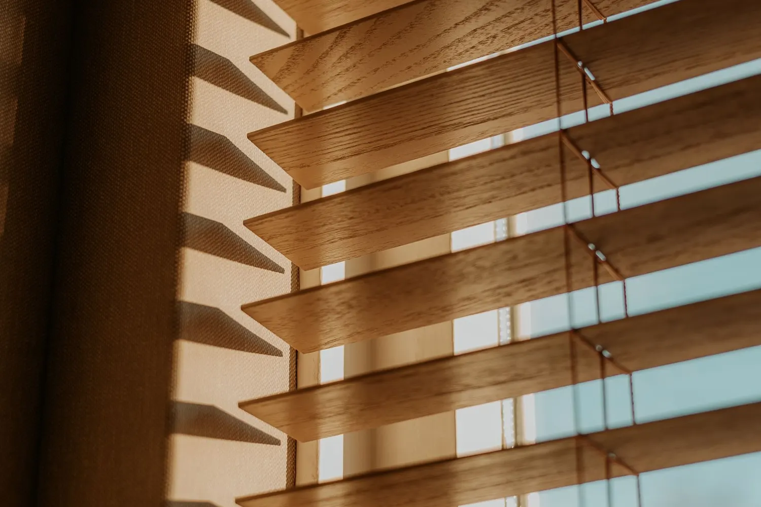 Wooden venetian blind with slats tilted to let in warm light